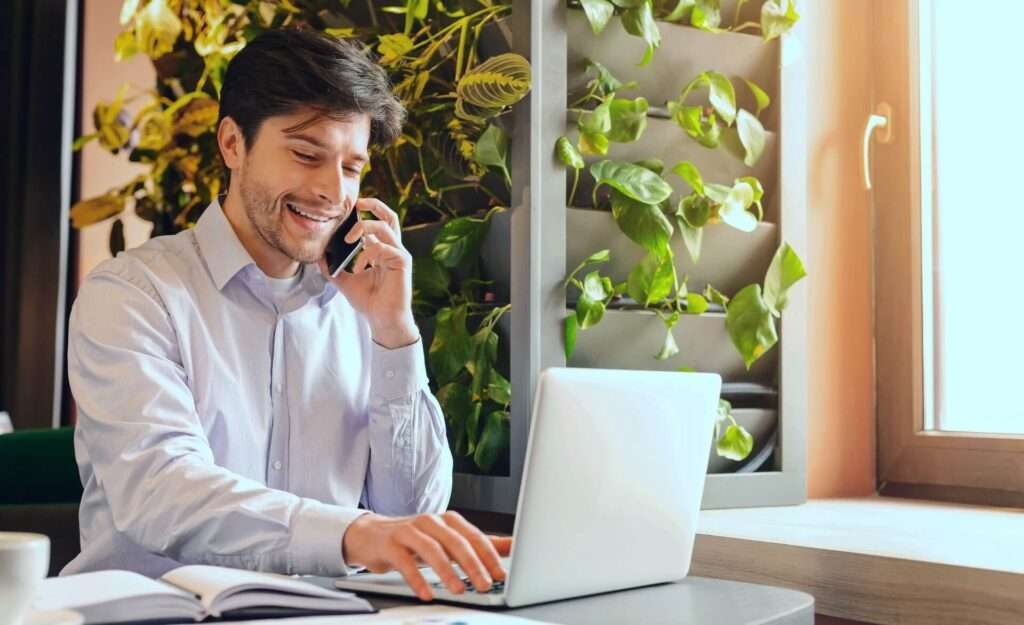 medium small business development cheerful businessman working on laptop and talking on phone in cafe free space 1